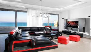 a living room with a black leather couch and a television at The Royal Penthouse in Bat Yam