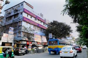 a bus driving down a busy city street with cars at Bothra Guest House in Kolkata