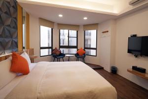 een hotelkamer met een bed en twee stoelen en een televisie bij Penghu Little Apple B&B in Magong