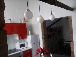 cocina con armarios rojos y microondas blanco en Casa Mamá Conchita Vivienda Vacacional, en Los Silos