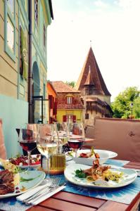 a table topped with plates of food and glasses of wine at Casa Georgius Krauss Sighisoara in Sighişoara