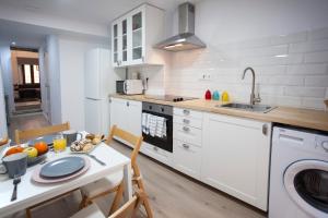 a kitchen with white cabinets and a table and a sink at Casa Severina in Alcoy