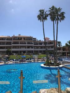 a large swimming pool with palm trees and a hotel at Apartment South Tenerife in San Miguel de Abona