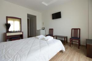 a bedroom with a white bed and two chairs at Flisvos Rooms in Livanates