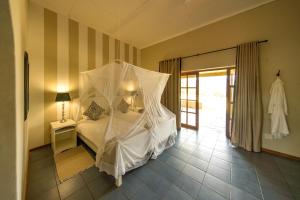 a bedroom with a bed with a mosquito net at Ghaub Nature Reserve & Farm - ONE Namibia in Groutfontein
