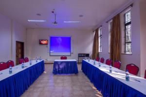 a conference room with blue tables and chairs and a screen at Chak Guesthouse & Conference Center in Nairobi