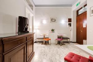 Il comprend un salon doté d'une télévision et d'une table avec des chaises. dans l'établissement 2 Passi Al Colosseo B&B, à Rome