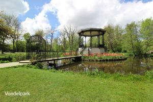 a bridge over a pond with flowers in a park at Romantic ground floor suite in Pijp near Sarphatipark in Amsterdam