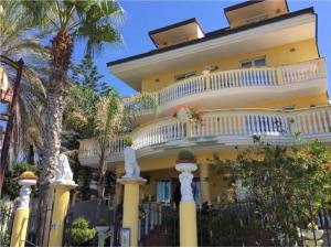 uma grande casa amarela com uma varanda e palmeiras em Cridda Hotel & Restaurant em Gizzeria