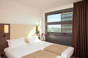 een hotelkamer met 2 bedden en een raam bij Séjours & Affaires Lille Europe in Lille