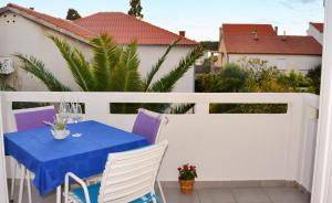 a table on a balcony with a blue table and chairs at Apartments Mike in Novalja