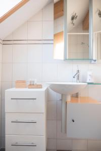 a white bathroom with a sink and a mirror at Apartment mit Dachterrasse & Sauna in Wangen im Allgäu