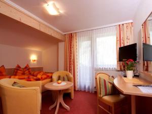 une chambre d'hôtel avec un lit, une table et des chaises dans l'établissement Haus Alpina, à Häselgehr