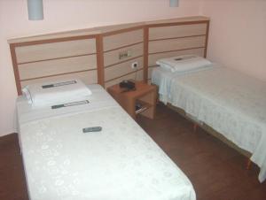 a room with two beds and a table with a phone at Hotel Gramado de Campos in Campos dos Goytacazes