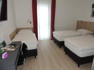 Zimmer mit 3 Betten und einem Schreibtisch in der Unterkunft AVIA Motel Bisamberg in Korneuburg