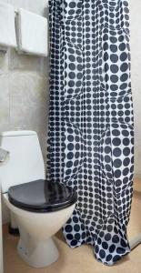 a bathroom with a toilet and a black and white shower curtain at Hotel Surte in Surte