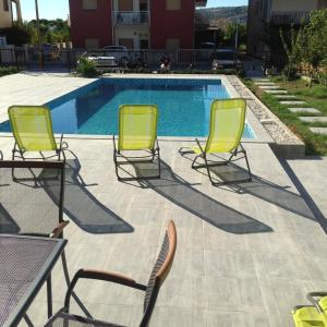 drie stoelen en een tafel naast een zwembad bij Rooms Chill Out Beach in Trogir