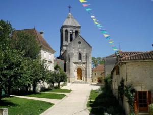 uma igreja com uma torre e um campanário com bandeiras em Au Pied du Chateau em Brantome en Perigord