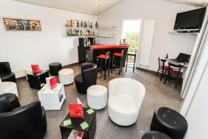 a living room with white chairs and a red table at Hôtel Restaurant Les Bruyères in Saint-Médard-en-Jalles