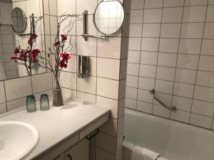 a bathroom with a sink and a vase with red flowers at Steiner Strandappartements Appartement 308 Süd- Landseite in Stein