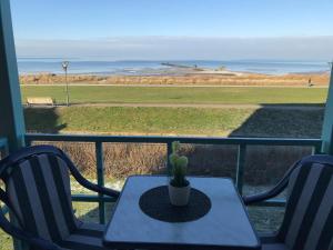 a table and chairs on a porch with a view of the ocean at Steiner Strandappartements Appartement 202 Seeseite in Stein