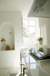 コインブラにあるCasa de Baixoのガラスのカウンターと窓が備わる白い客室です。