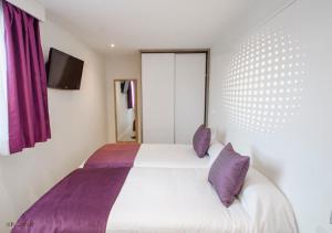 1 dormitorio con cama blanca y almohadas moradas en Apartamentos Ponent en Paguera