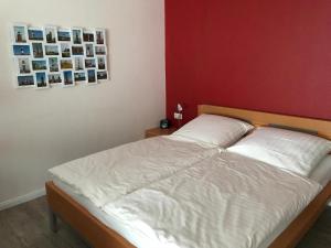 a bedroom with a white bed and a red wall at Steiner Strandappartements Appartement 303 Seeseite in Stein