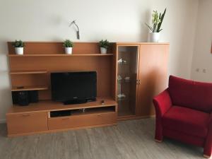 a living room with a tv and a red chair at Steiner Strandappartements Appartement 303 Seeseite in Stein