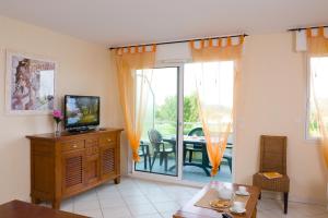 sala de estar con TV y mesa de comedor en Madame Vacances Les Appartements de Fontenelles, en LʼAiguillon-sur-Vie