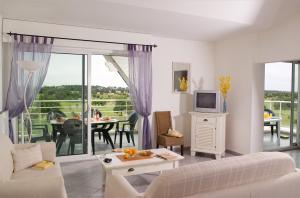 a living room with a couch and a tv and a balcony at Madame Vacances Les Appartements de Fontenelles in LʼAiguillon-sur-Vie