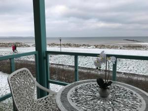 a table and chair on a balcony with snow on the beach at Steiner Strandappartements Studio-Appartement 203 Seeseite in Stein