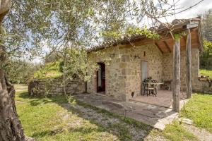 una vista exterior de una casa de piedra con una mesa en La casina degli olivi, en Seggiano