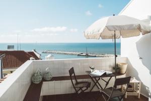 balcón con mesa, sillas y sombrilla en Apartamento 2 quartos by WOT Ericeira Lodge en Ericeira