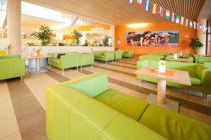 ein Restaurant mit grünen Sofas und Tischen in einem Zimmer in der Unterkunft JUFA Hotel Leibnitz in Leibnitz