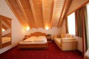 a bedroom with a bed and a couch and a chair at Hotel Garni Litzner in Ischgl