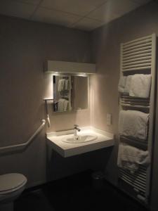 La salle de bains est pourvue d'un lavabo, d'un miroir et de serviettes. dans l'établissement Logis Hotel des Bourbons, à Montluçon