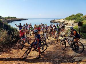 grupa ludzi jeżdżących rowerami na szlaku blisko wody w obiekcie Agriturismo La Palascìa Masseria Agreste w mieście Otranto