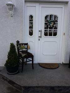 a white door with a chair and a plant next to it at Kieselwitzer Stübchen Bremsdorfer Weg 9 in Kieselwitz