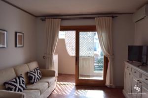 un soggiorno con divano e porta scorrevole in vetro di Villaggio Smeralda by Sardegna Smeralda Suite a Porto Rotondo
