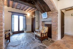a living room with a stone fireplace and a chair at La villa della quercia in Seggiano