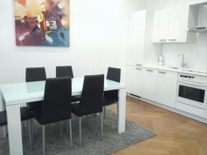 a white kitchen with a white table and black chairs at Avenue de La Paix - L'Exclusif in Strasbourg