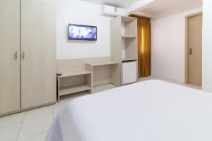 1 dormitorio blanco con 1 cama y TV en la pared en Hotel Kimar, en Tramandaí