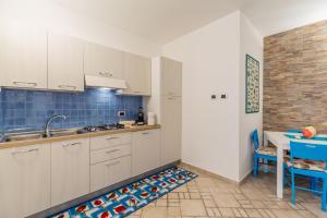 a kitchen with white cabinets and a blue tiled wall at casavacanza golfo aranci in Golfo Aranci