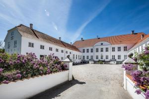 una fila de edificios blancos con flores púrpuras en Kragerup Gods, en Ruds-Vedby