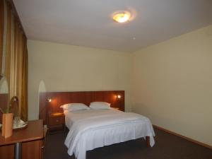 a bedroom with a white bed and a wooden headboard at Gura Padurii in Sinaia