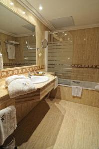 
a bath room with a tub, sink, and mirror at Hotel Alisi in Aranda de Duero
