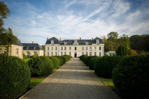 une grande maison blanche avec une rangée de buissons dans l'établissement Château de Courcelles - Relais & Châteaux, à Courcelles-sur-Vesle