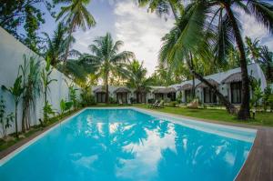 un complejo con piscina con palmeras y cabañas en Palaka Resort en General Luna