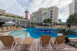 フロリアノポリスにあるIl Campanario Villagio Resort Apto Studio 2111の椅子と建物のある大きなプール